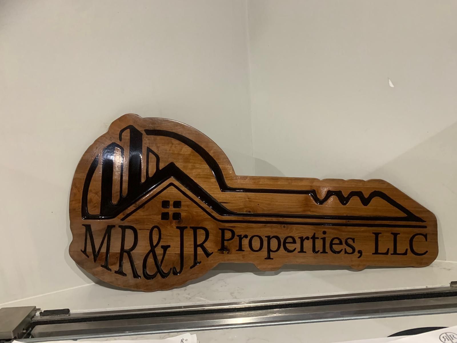 A wooden key shaped sign for mr & jr properties llc