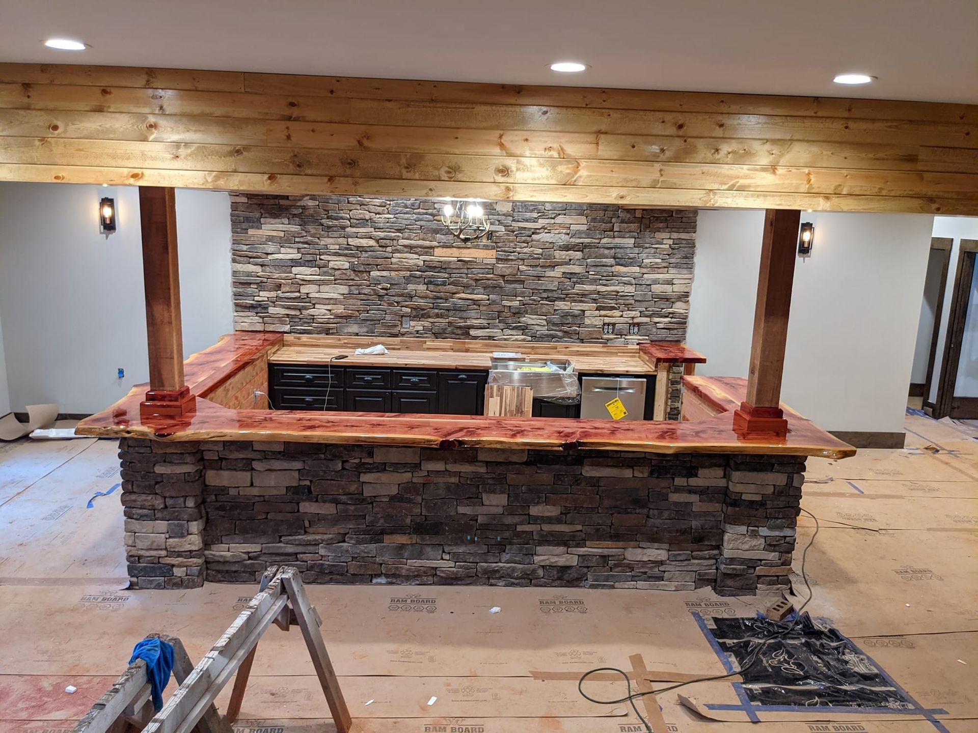 A kitchen with a stone wall and a wooden bar.