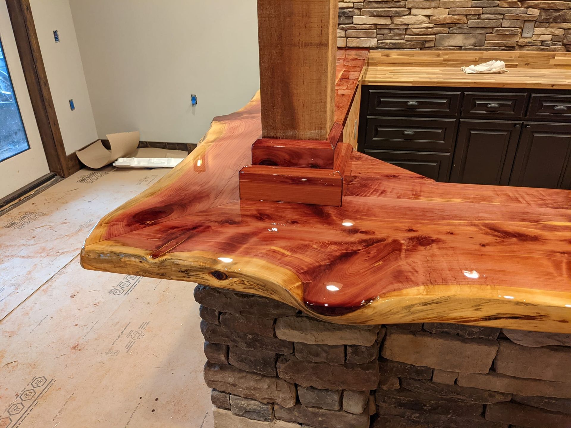 A kitchen with a wooden counter top and a stone wall.