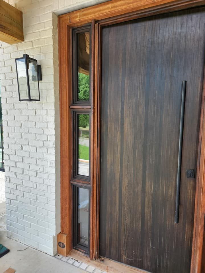 A wooden door with a black handle is on a white brick wall.