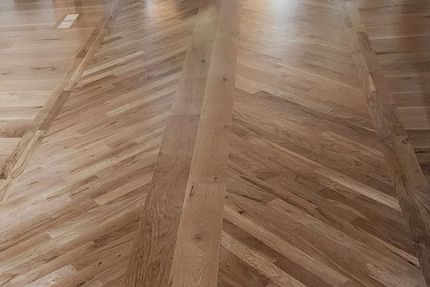 A close up of a wooden floor with a herringbone pattern.