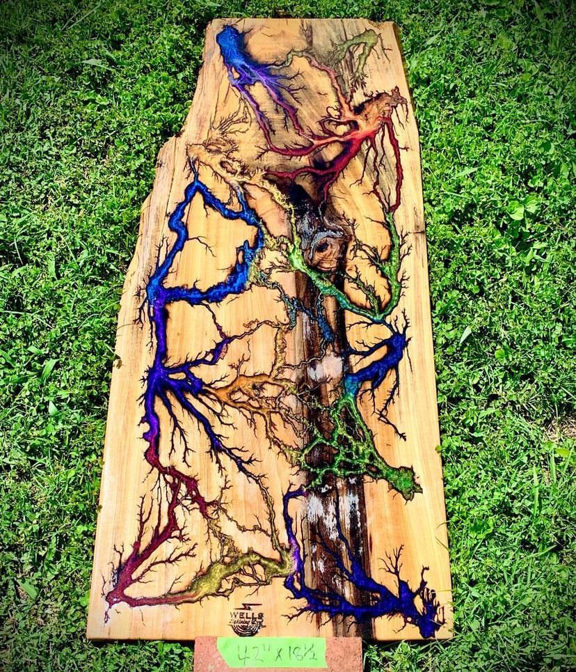 A wooden board with a colorful design on it is sitting on top of a lush green field.