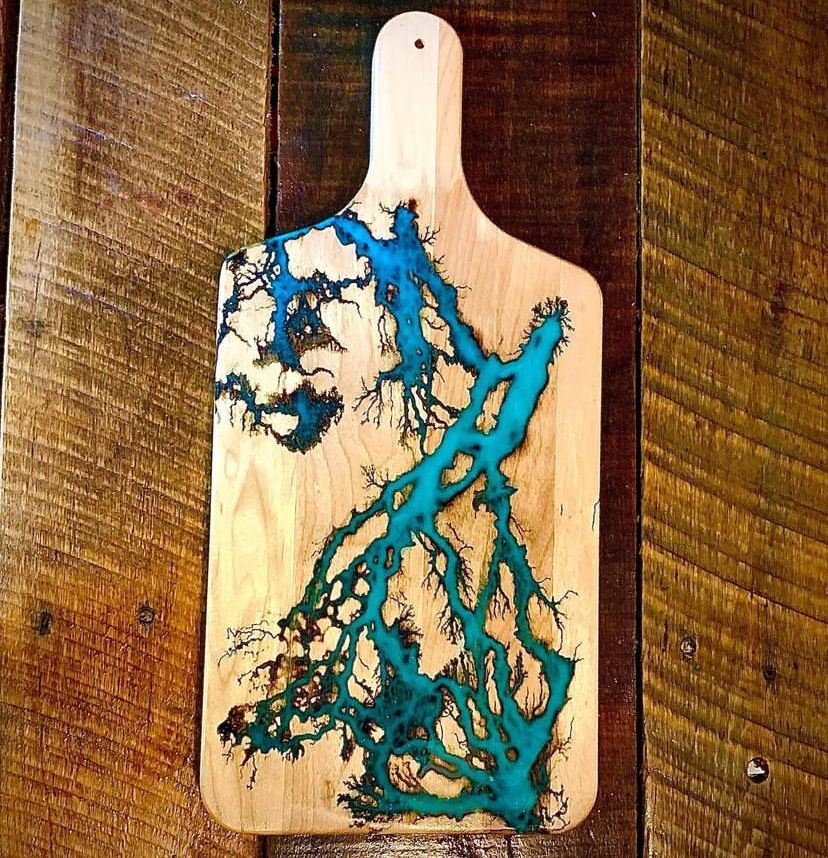 A wooden cutting board with a blue design on it is sitting on a wooden table.
