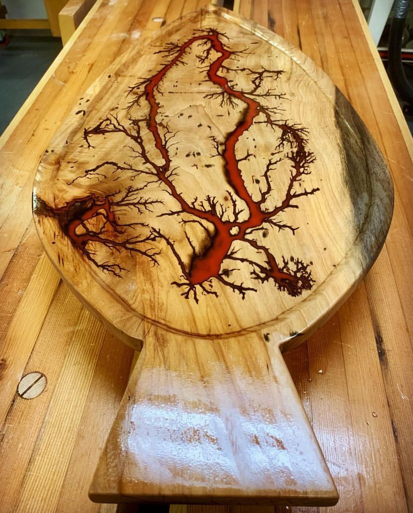 A wooden cutting board with a tree design on it is sitting on a wooden table.