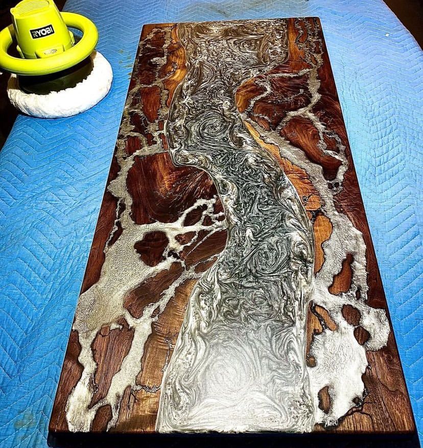 A wooden table is sitting on a blue blanket next to a polisher.