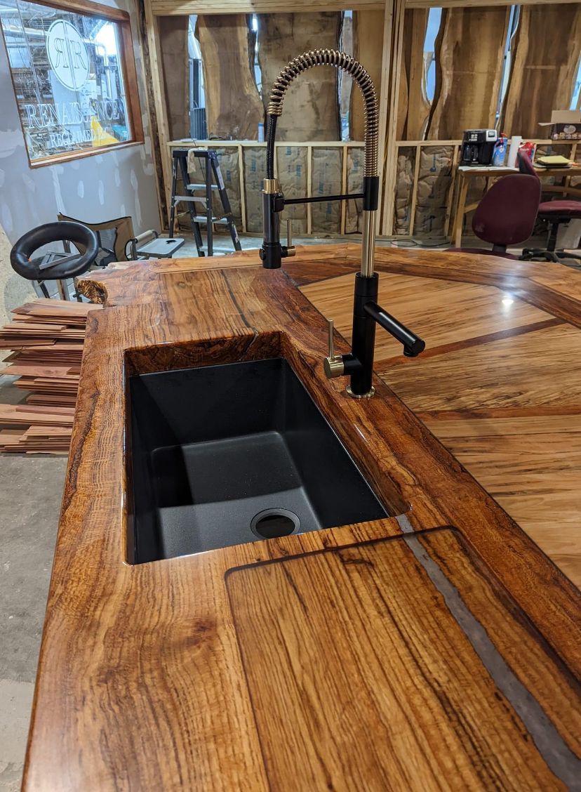 A kitchen sink is sitting on top of a wooden counter.