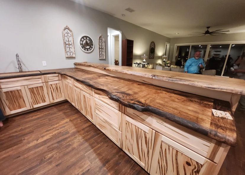 A man is standing behind a wooden counter in a kitchen.
