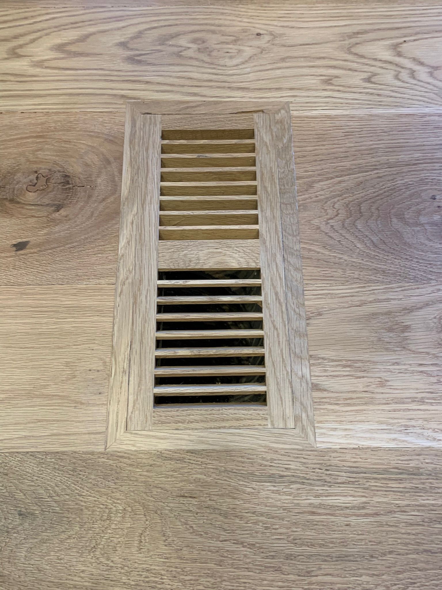 A wooden floor with a vent on it.