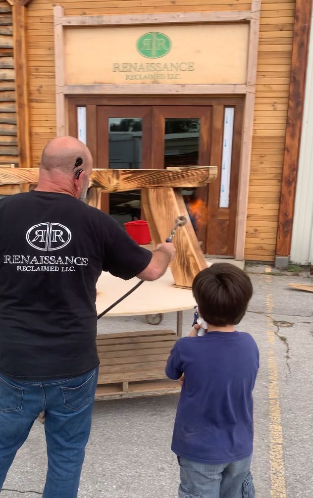 A man and a boy are standing in front of a wooden building.