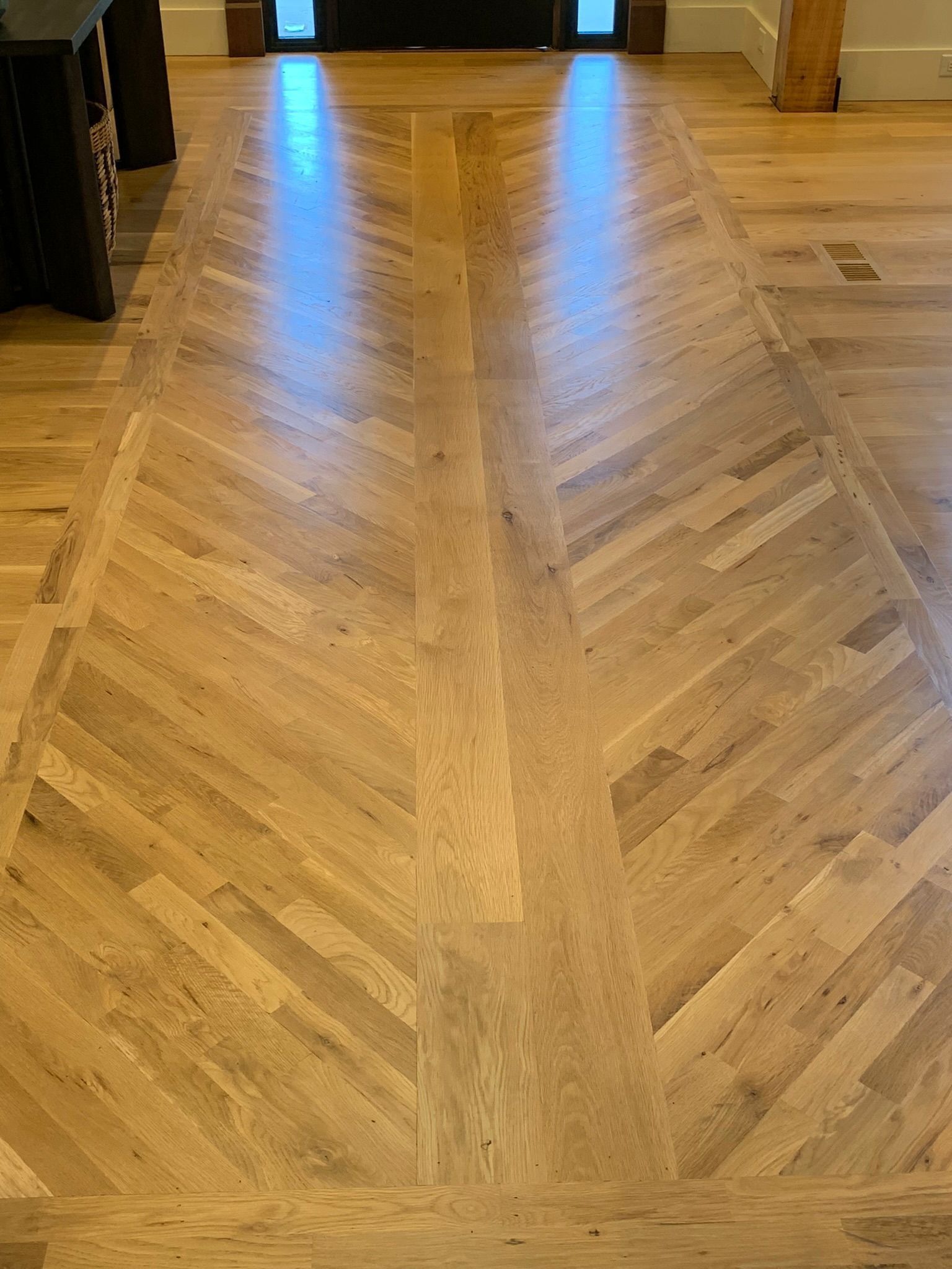A wooden floor with a chevron pattern in a living room.