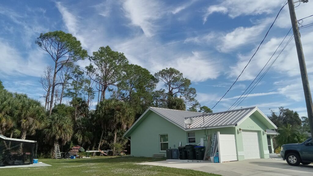 A person holding a baby up in the air indoors near a window, baby smiling.