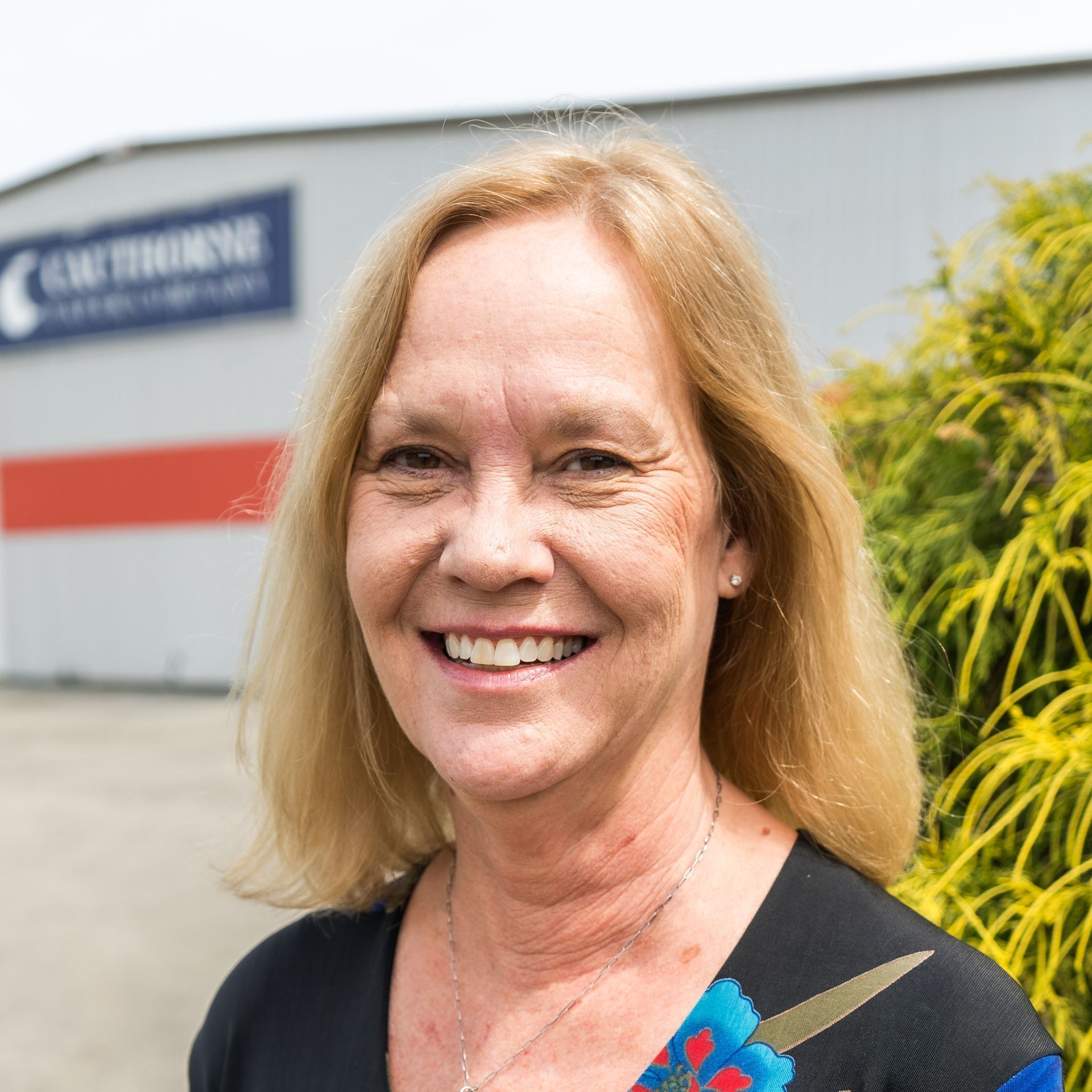 A woman is smiling in front of a building.