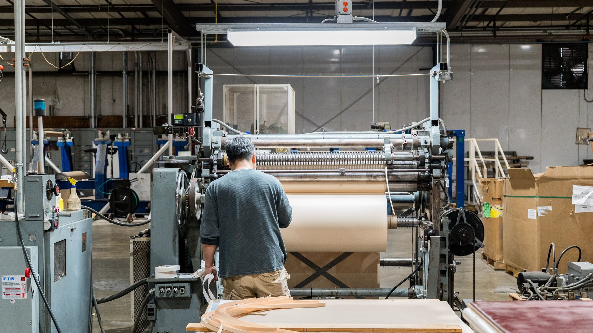 A man is standing in front of a machine in a factory.