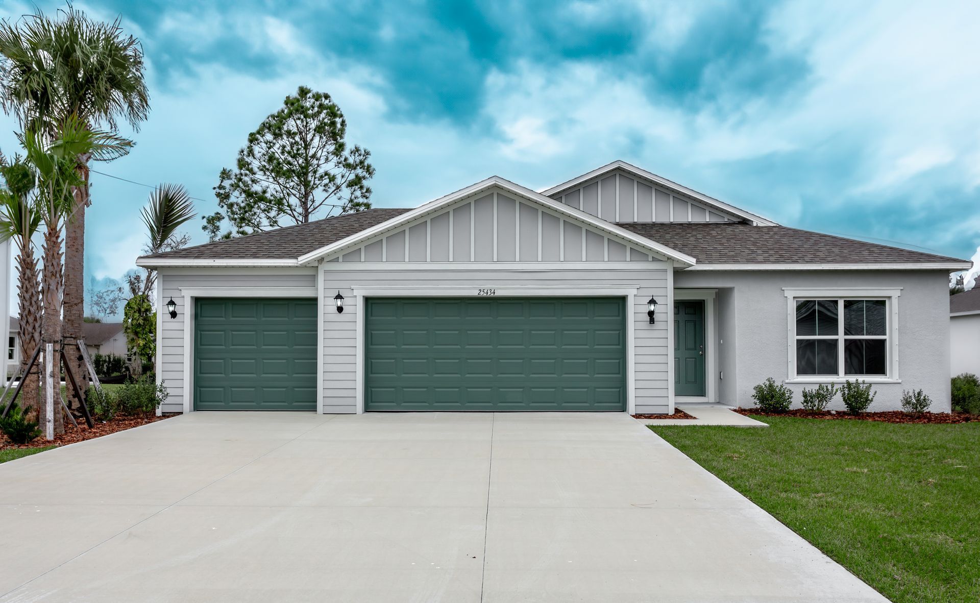 A white house with green garage doors and a driveway