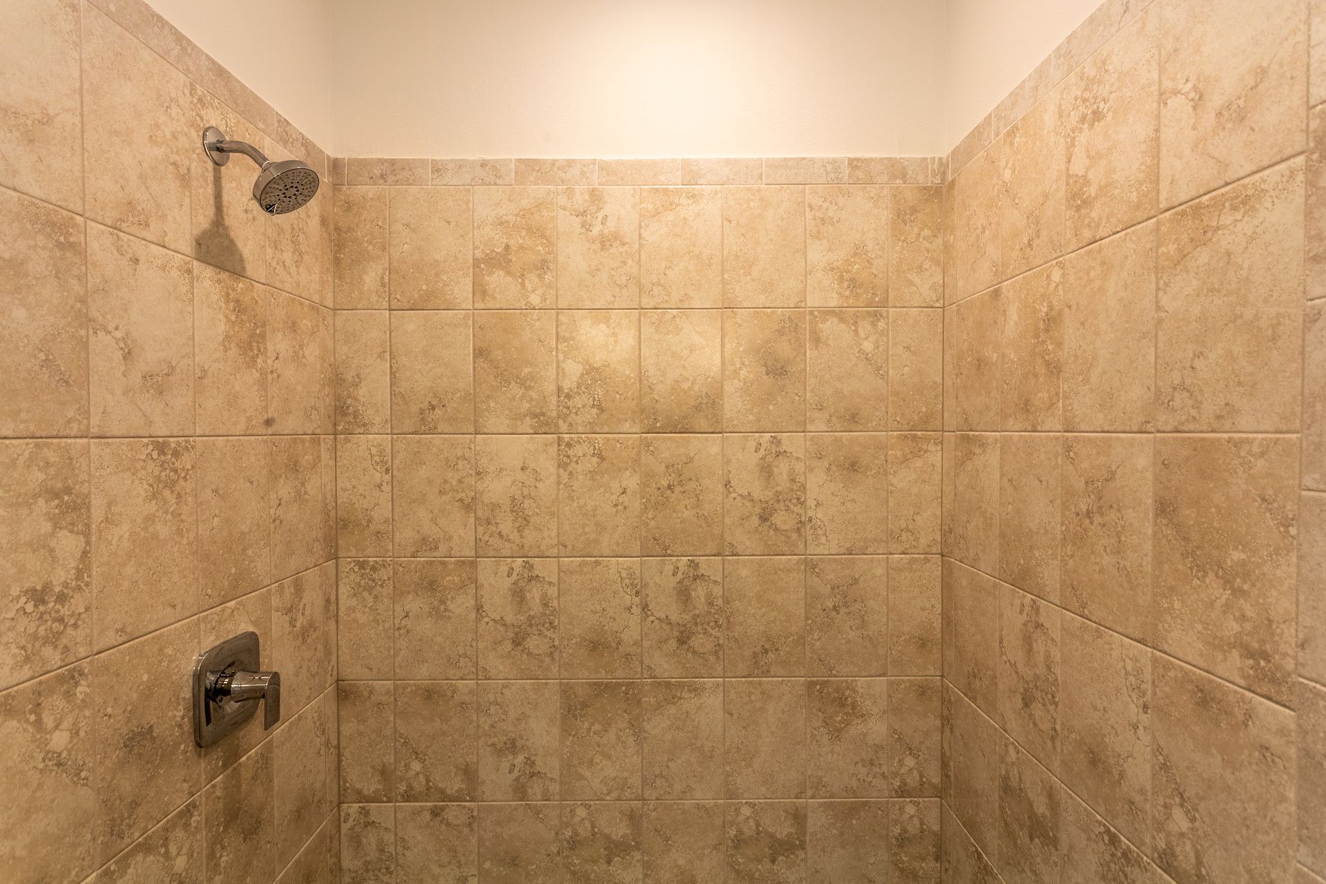 A shower with tiled walls and a shower head.
