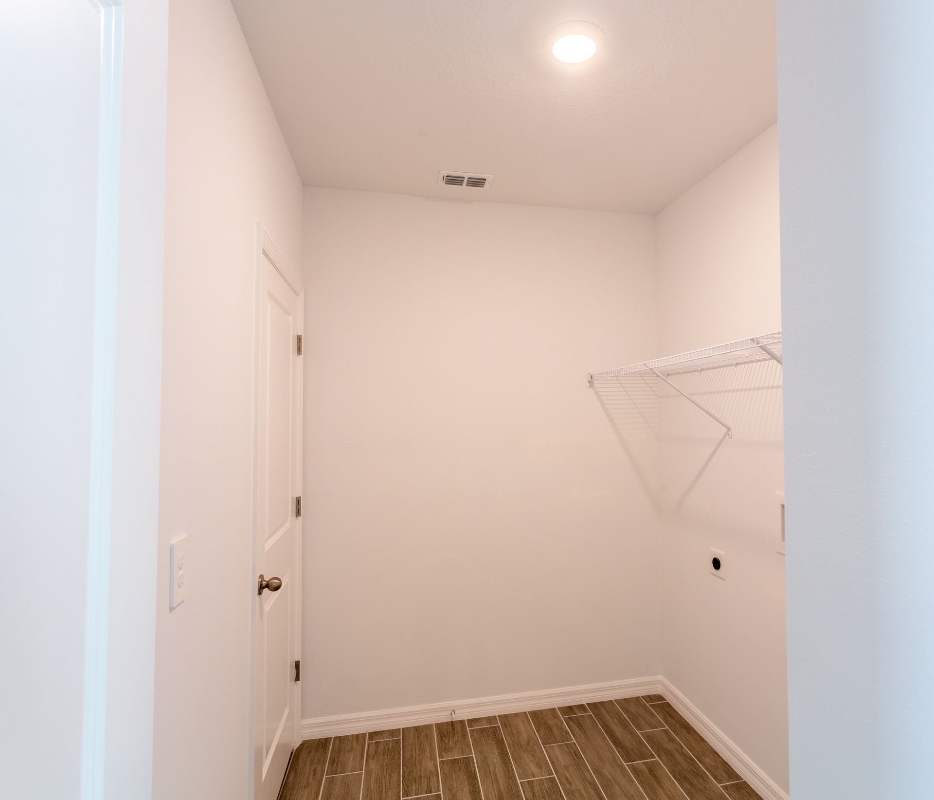 A laundry room with a wooden floor and white walls.