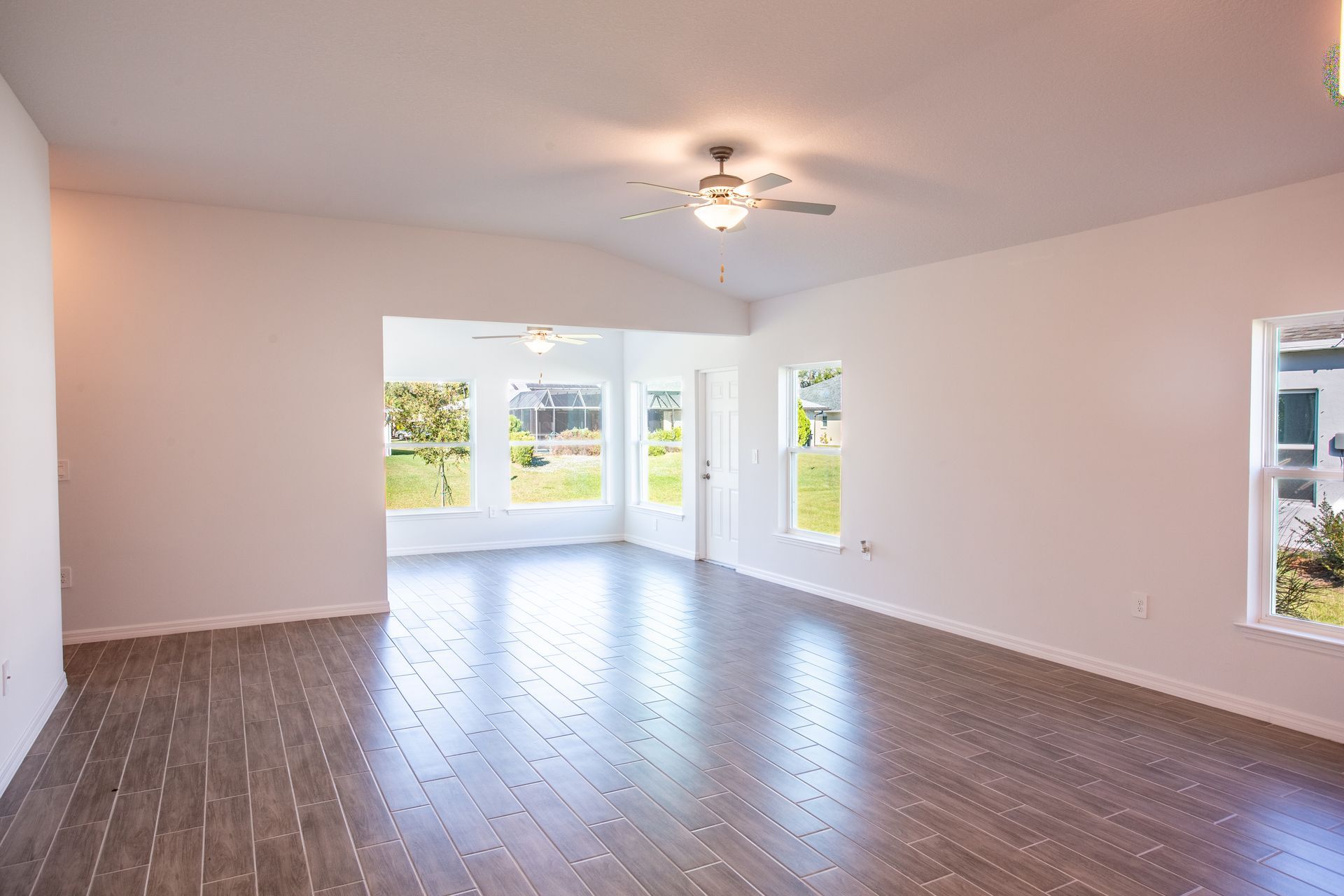 An empty living room with hardwood floors and a ceiling fan.
