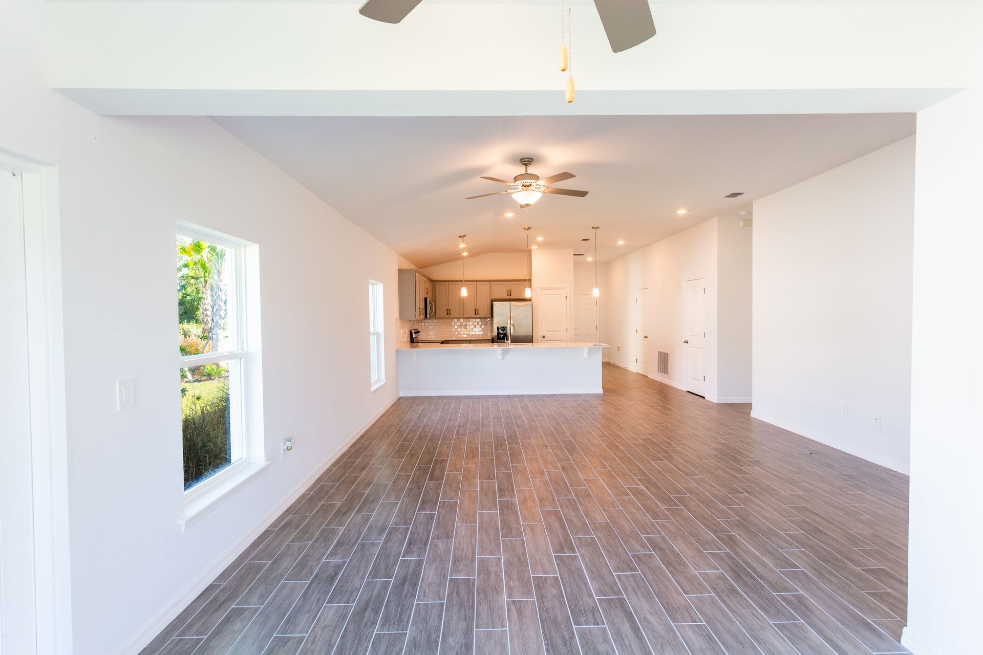 An empty living room with hardwood floors and a ceiling fan.