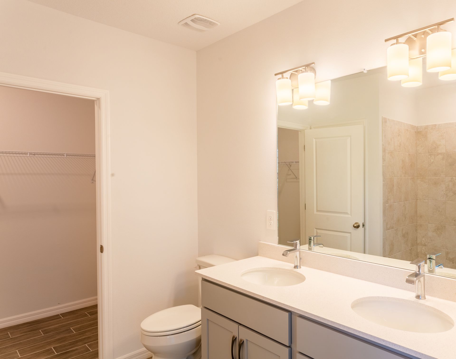 A bathroom with two sinks , a toilet , and a large mirror.