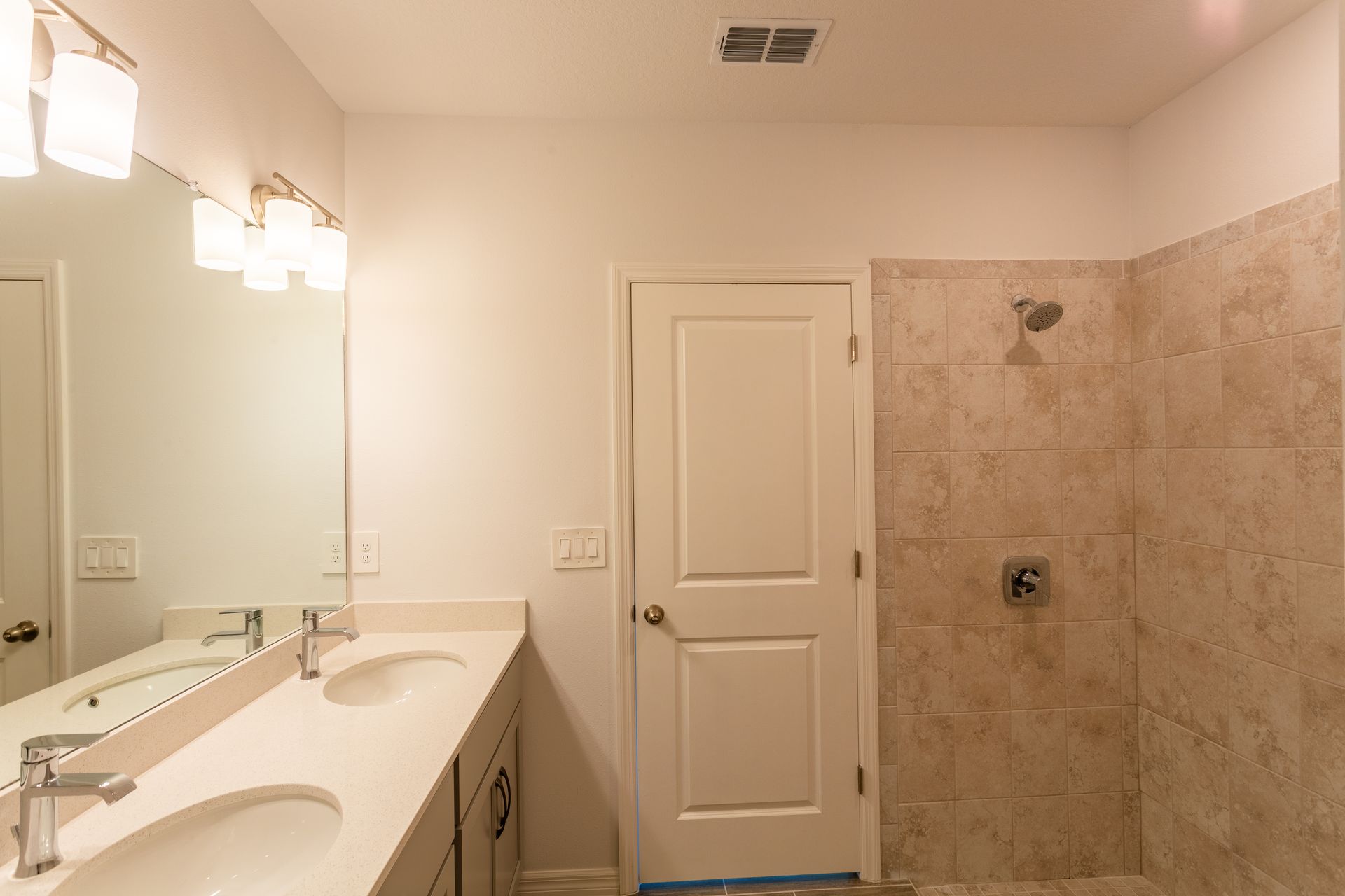 A bathroom with two sinks and a walk in shower.
