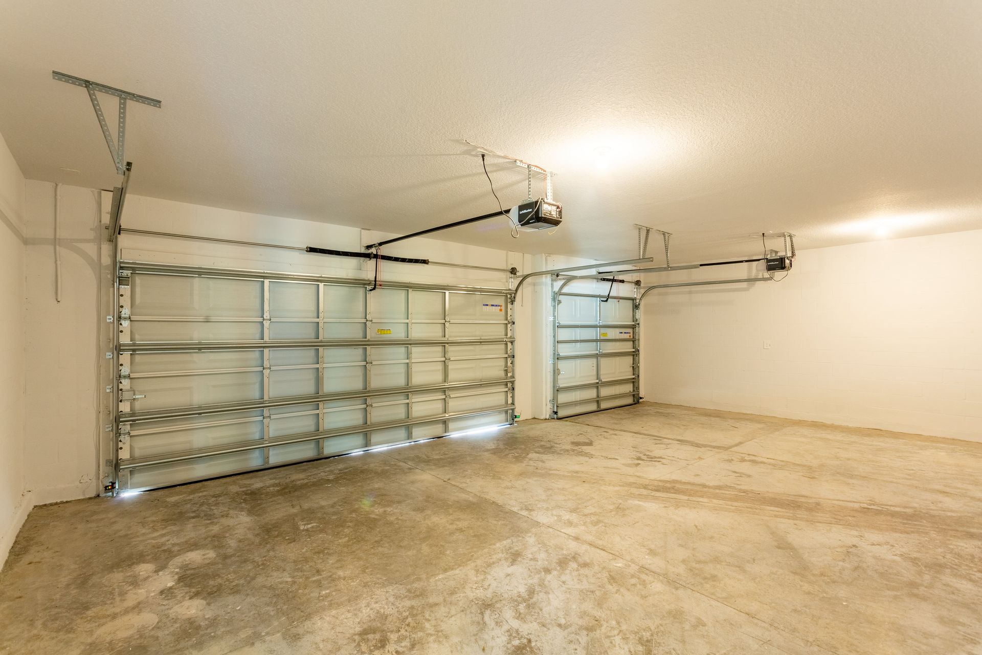 An empty garage with a garage door open and a ceiling fan.