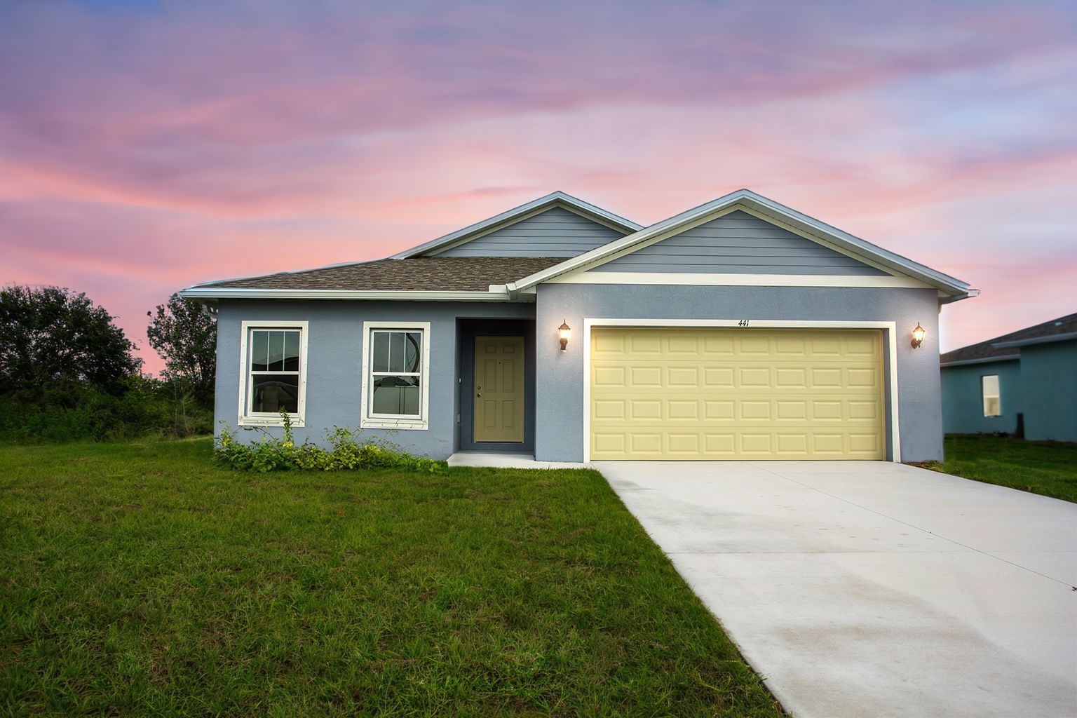 A blue house with a yellow garage door is for sale.
