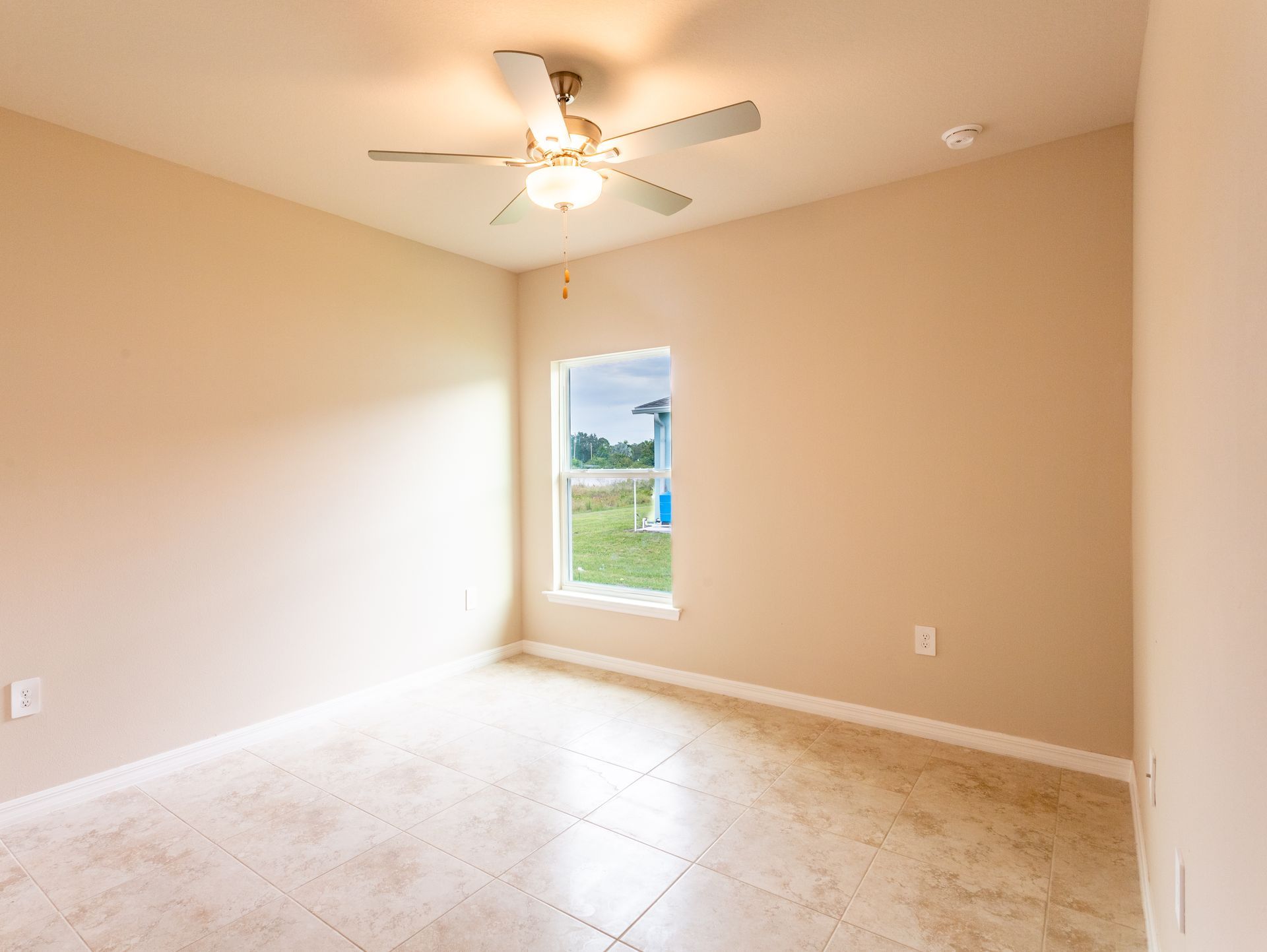 An empty bedroom with a ceiling fan and a window.