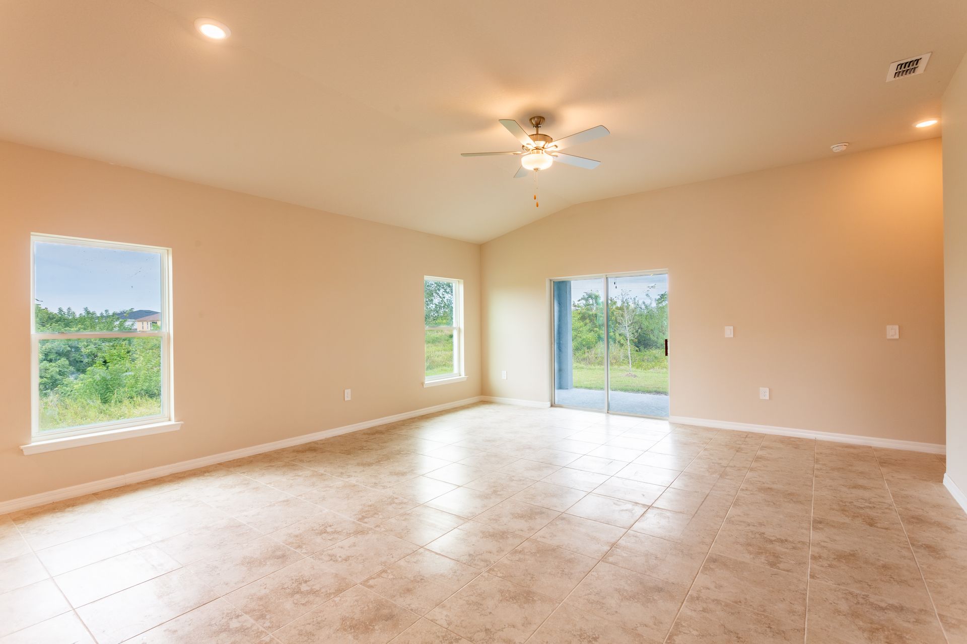 An empty living room with tile floors and a ceiling fan.