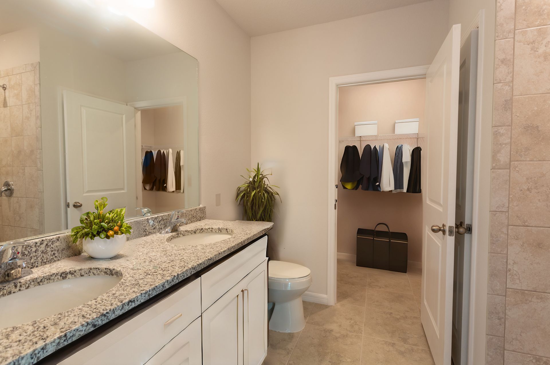 A bathroom with two sinks , a toilet , and a walk in closet.
