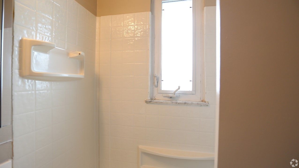 A bathroom with a shower and a window.