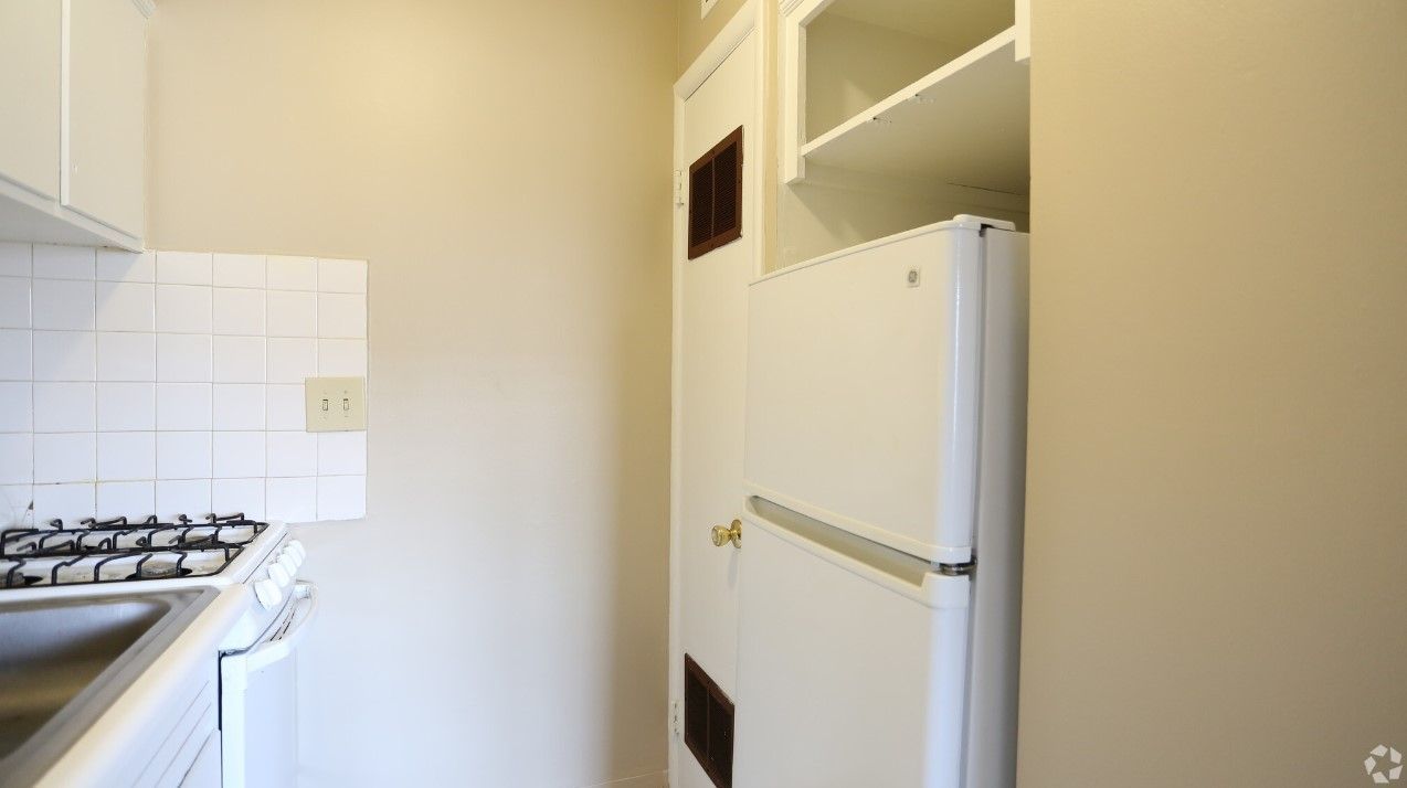 A kitchen with a refrigerator , stove , sink and cabinets.