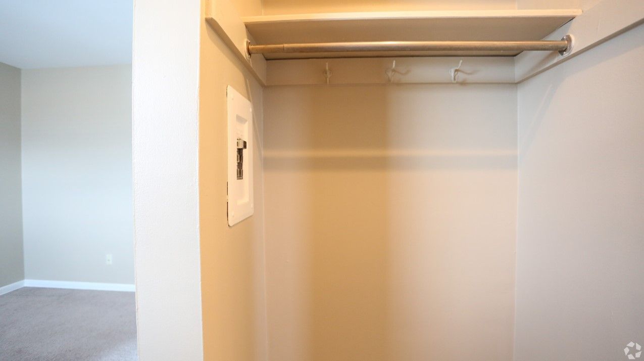 An empty walk in closet with a shelf and clothes rack.