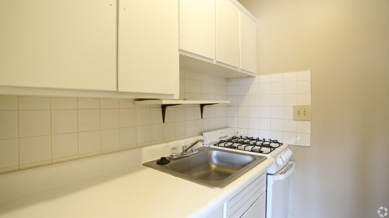 A kitchen with white cabinets and a stove and sink