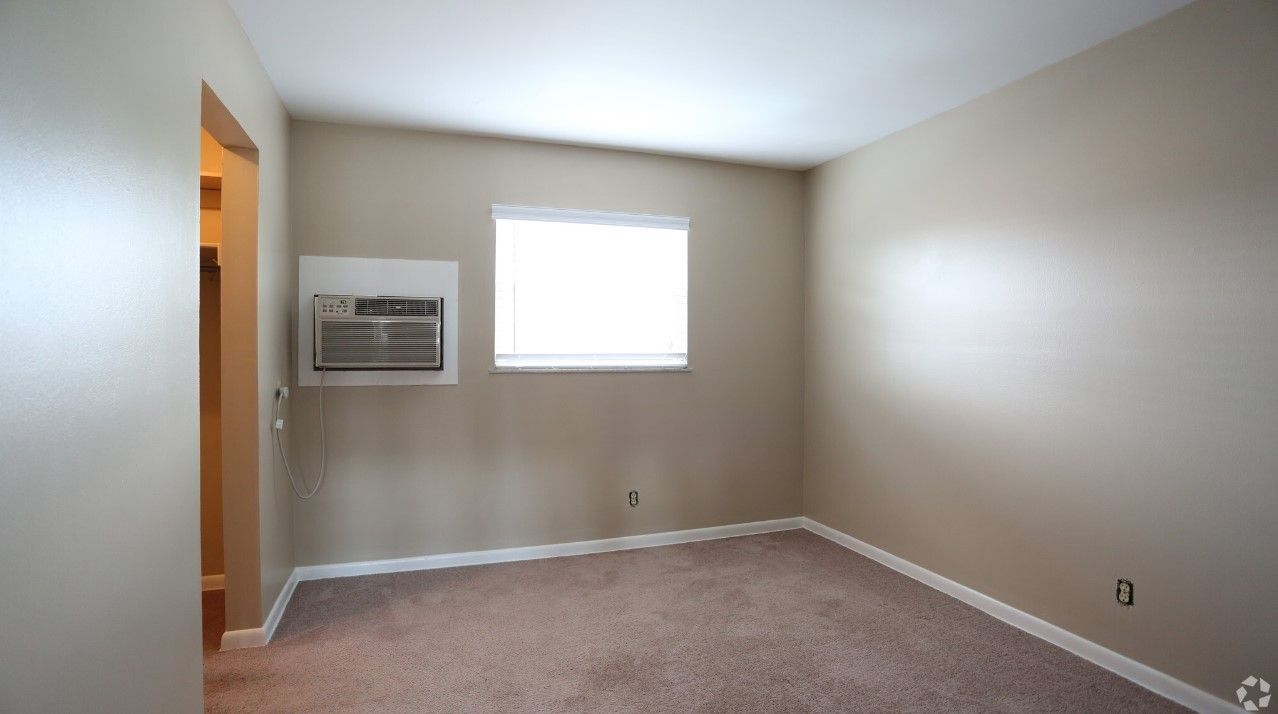 An empty room with a window and air conditioner