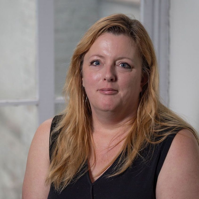 A woman without a face is wearing a suit and white shirt