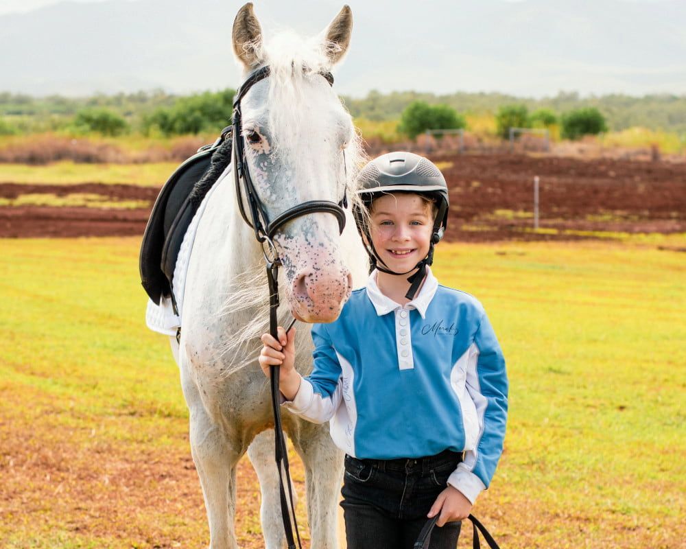 A Young Boy is Standing Next to a White Horse in a Field — Meraki Equestrian Centre in Mareeba, QLD