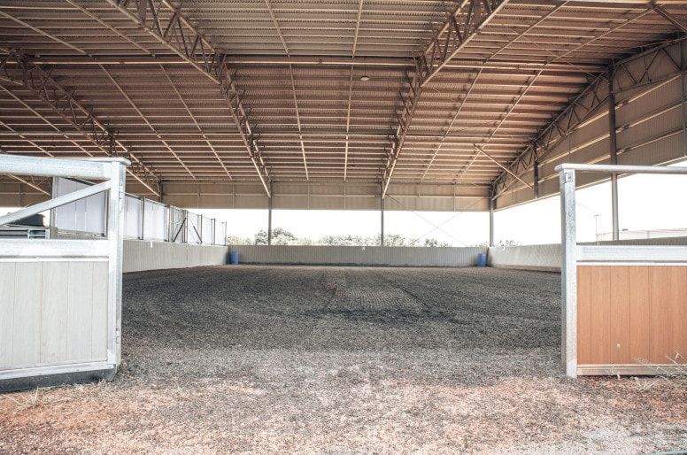 A Large Empty Indoor Riding Arena With a Wooden Fence — Meraki Equestrian Centre in Mareeba, QLD