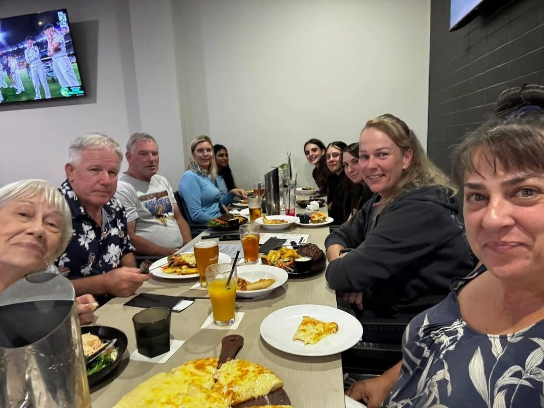 A Group of People Are Sitting at a Table With Plates of Food and Drinks — Meraki Equestrian Centre in Mareeba, QLD