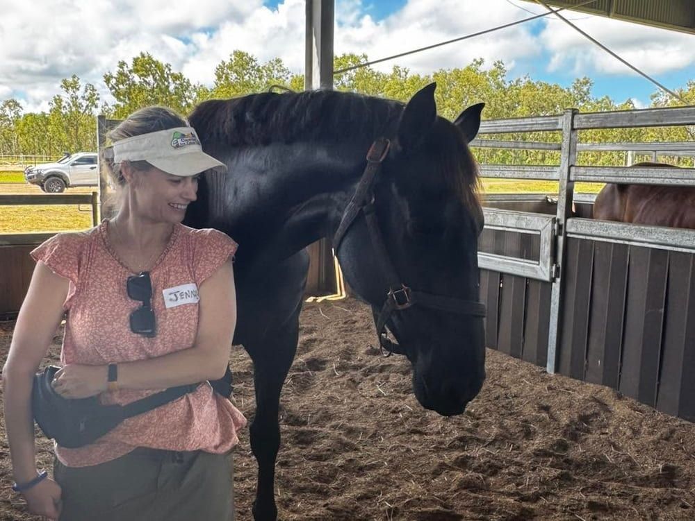 A Woman is Standing Next to a Black Horse in a Stable — Meraki Equestrian Centre in Mareeba, QLD