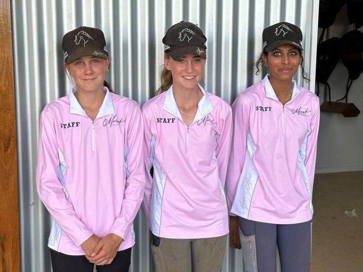 Three Women Wearing Pink Shirts and Hats Are Standing Next to Each Other — Meraki Equestrian Centre in Mareeba, QLD