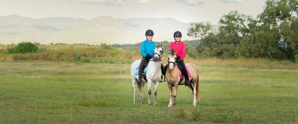 Two Children Are Riding Horses in a Field — Meraki Equestrian Centre in Mareeba, QLD