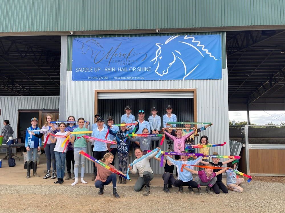 A Group of People Are Standing in Front of a Building Holding Ribbons — Meraki Equestrian Centre in Mareeba, QLD