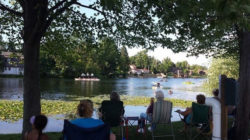 A group of people are sitting under a tree overlooking a lake