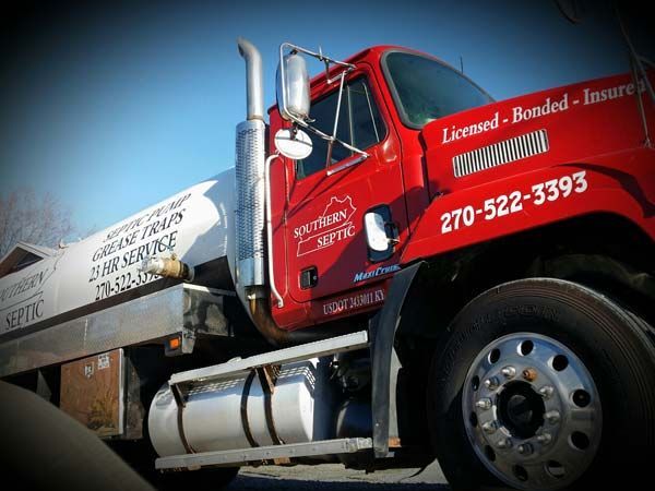Red Southern Septic truck featuring contact information and service details, parked outside on a sunny day.