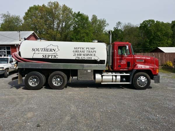 A red and white Southern Septic tanker truck parked on a gravel lot with trees in the background.