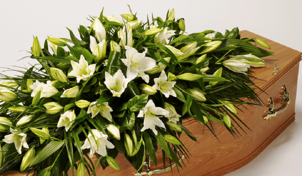 A bunch of white lilies placed on a wooden coffin