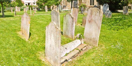 Graves in a churchyard, several of which are leaning