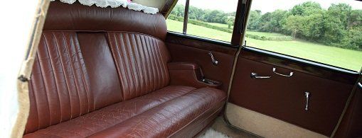 The interior of a car, furnished in wood and red leather