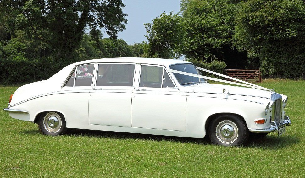 A white wedding car with flowers in the rear window