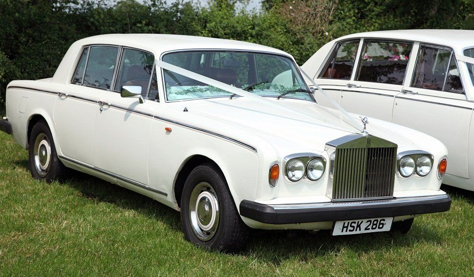 A white wedding car with a decoration in the front window